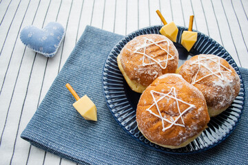 Happy Hanukkah banner. A traditional treat of doughnuts with David star and dreidel made from cheese and biscuit sticks. Copy space