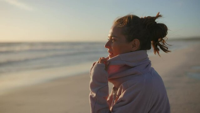 elegant 40 years old woman in cosy sweater at the beach in the evening relaxing.