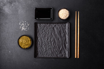 Empty plate with wooden sticks for Asian food on a dark concrete background