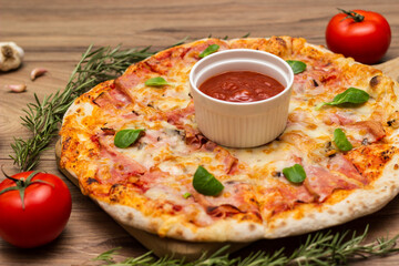 Freshly baked pizza with ham, tomato, and cheese