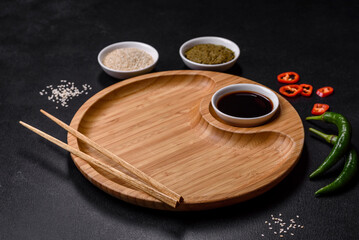 Empty plate with wooden sticks for Asian food on a dark concrete background