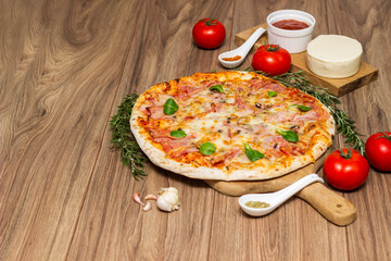 Freshly baked pizza with ham, tomato, and cheese