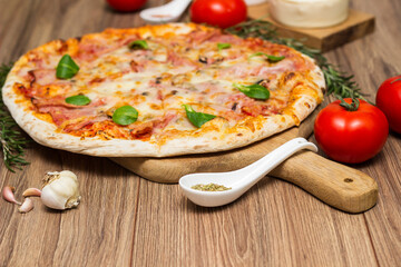 Freshly baked pizza with ham, tomato, and cheese