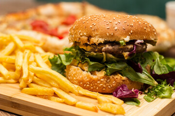 Fresh tasty hamburger and french fries with salad on cutting board