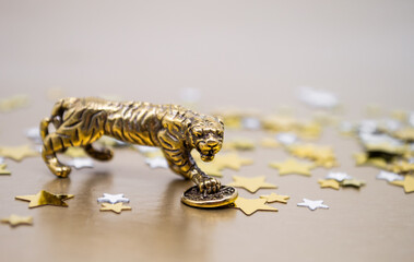 A bronze figure of a tiger with a coin on a background of golden stars, copy space. Wishes of power, financial well-being and wealth