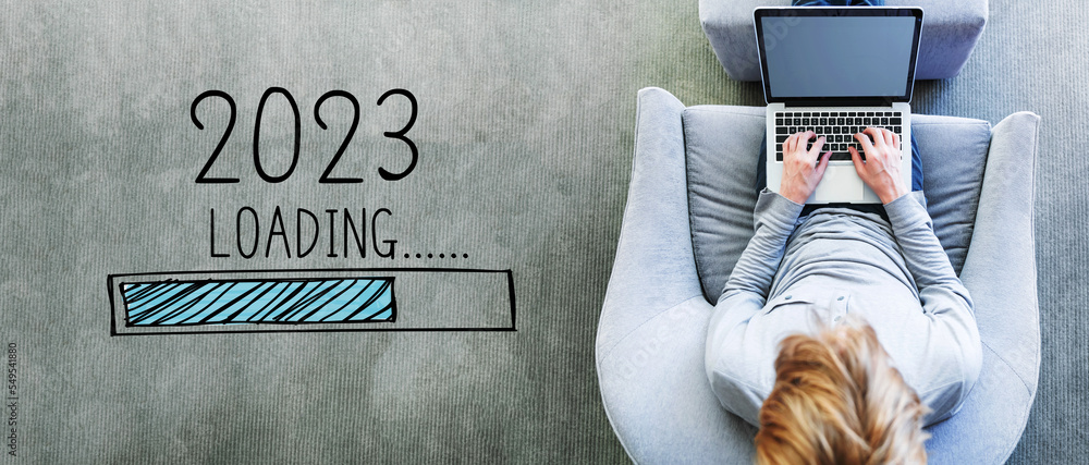 Poster loading new year 2023 with man using a laptop in a modern gray chair