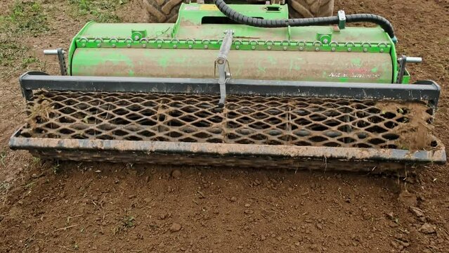 Close-up rotary cultivator attachment of small tractor. Ground leveler. Moving soil. Mini skid steer loader clear the construction site. Land work. Territory improvement.