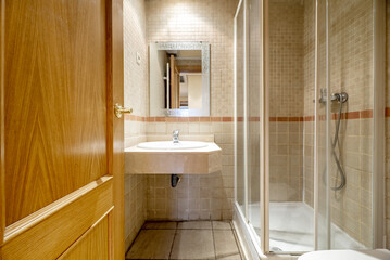 Small bathroom with walk-in shower with glass doors and white trim, marble sink counter, and tiled...