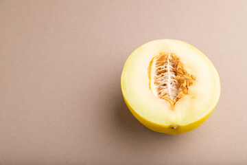 Sliced ripe yellow melon on brown pastel background. Side view, copy space.