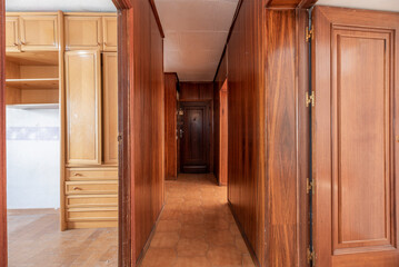 Corridor of an urban house with stoneware floors and walls covered with wood to match the doors of the rooms