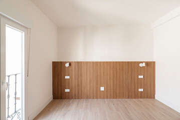 Empty bedroom with wooden headboard with attached wall sconces and matching tiled floors and plain white painted walls