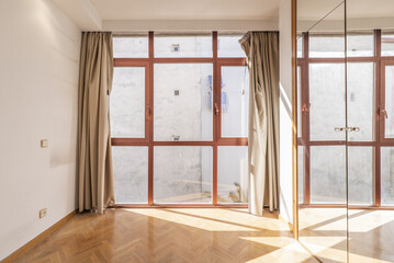 Obraz premium Empty bedroom with no view glass wall, red anodized aluminum windows and wardrobe with mirror doors and lock