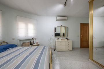 Old bedroom with stoneware floors, a bed with a gold metal frame and a built-in wardrobe with...