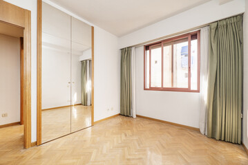 Empty bedroom with built-in wardrobe with trunk and folding mirror doors, red anodized aluminum...