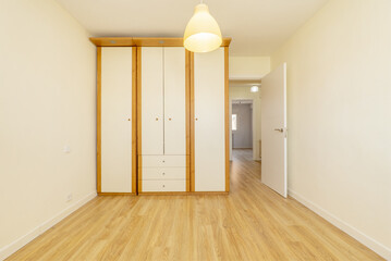 room with a built-in wardrobe with two-tone wooden doors and drawers in the center on floating oak...