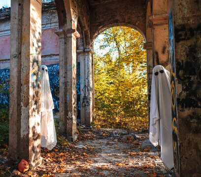 A funny image of two people in ghost costumes and sunglasses in an abandoned building