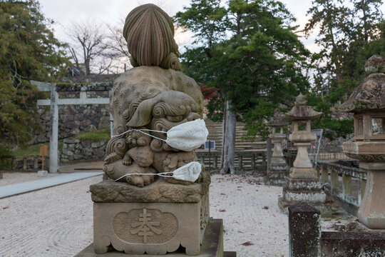 日本の神社前のマスクを付けてる狛犬の様子