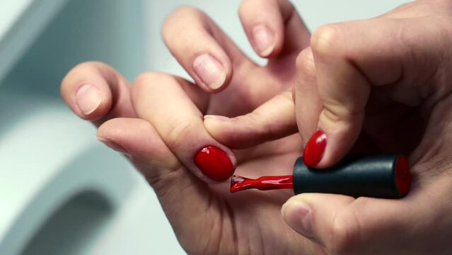 the girl does a manicure, paints her legs, removes varnish. close-up, trims cuticles, covers with base