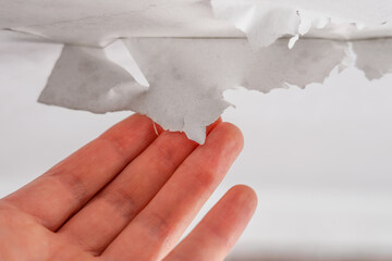 Hand peeling paint on bathroom ceiling rotting due to water leakage