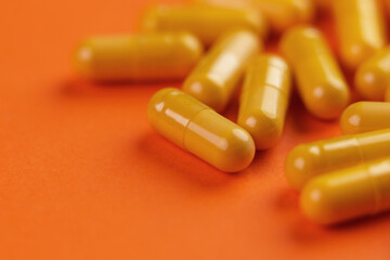 Colored yellow pharmaceutical medical capsules on a orange background