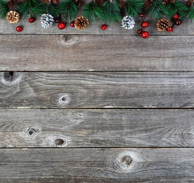 Merry Christmas or happy New Year background with fir tip tree branches and gold silver pine cones on rustic wood