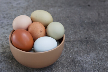 colorful organic eggs in a bowl on the grey stone background