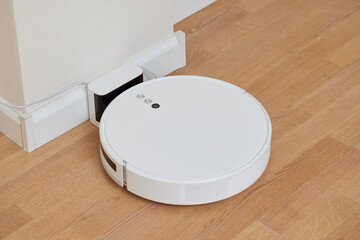 robotic vacuum cleaner on a laminated wooden floor Smart floor cleaning technology Charging dock...