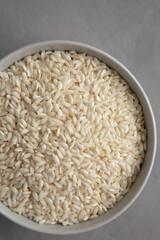 Raw Organic Carnaroli Rice in a Bowl on a gray background, top view. Overhead, from above, flat lay.