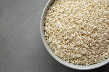 Raw Organic Carnaroli Rice in a Bowl on a gray background, top view. Overhead, from above, flat lay. Space for text.