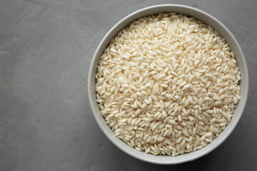 Raw Organic Carnaroli Rice in a Bowl on a gray background, top view. Overhead, from above, flat lay. Copy space.