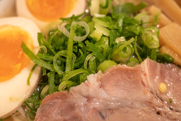 Close up view at chop leek, sliced pork Chash, and boiled egg on the top of Japanese ramen noodle soup. 