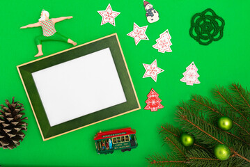 Christmas / New Year composition with frame copy space, fir branches, and Christmas baubles on green background. Flat lay, top view festive holiday mockup.