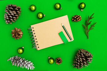 Mary Christmas layout. notepad and free space for text. Christmas decorations, Christmas toys, cones. Goals for the new year. mock up notebook and pencil on green background