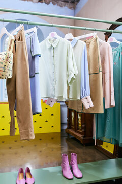 Vertical shot of modern outfits on clothes rails in modern dress-making shop