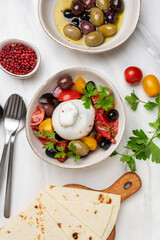 Italian burrata cheese salad with tomatoes, olives and olive oil.