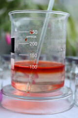 Alcohol solution of an indicator dye Congo red is on the surface of a water solution in a beaker.