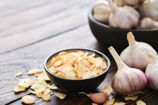 Bowl of dried garlic flakes. Garlic cloves and heads.