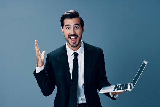 Man business looking at laptop and working online smiling with teeth surprised hand up via internet in business suit video call business talks win on blue background copy place