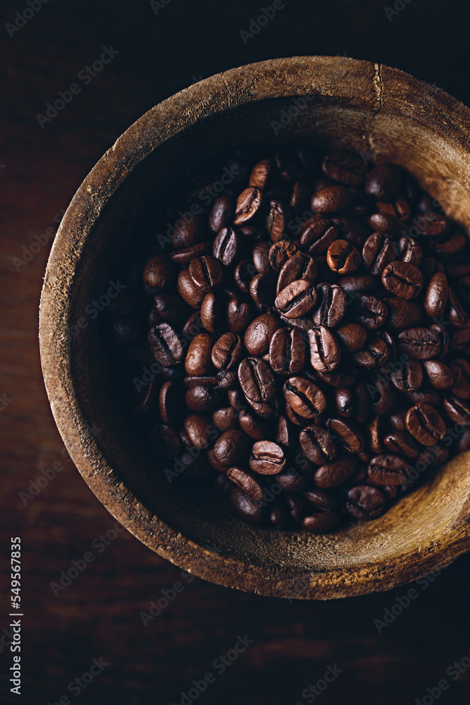 Wall mural Dark coffee beans in a rustic wooden cup. Close-up