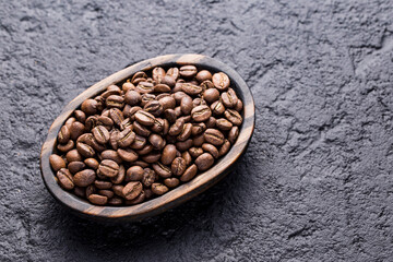 Roasted coffee beans on a plate, on a dark background, close-up image, space for text