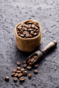 Roasted coffee beans in a cloth sack, on a dark background, close-up image, space for text