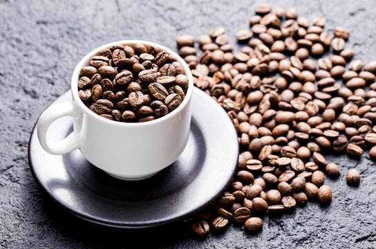 Roasted coffee beans in a cup, on dark background, close-up image, space for text