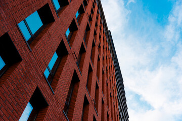 facade of an office building made of red brick against a blue sky, bottom view