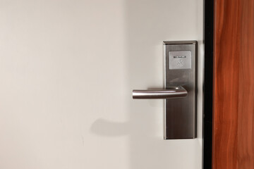 White door hotel room with modern stainless electronic lock with handle. Hotel key card digital...
