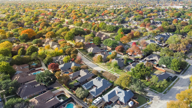 Subdivision sprawl colorful fall foliage, row of single family houses expanding to horizontal line near Dallas, Texas, US
