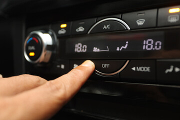 Fototapeta na wymiar driver presses off button to turn off ac on luxury car dashboard