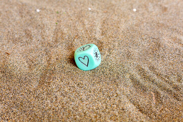 Weather prediction. Blu cube with heart and weather symbols. Funny gambling dice on sand. Saint Valentines concept. Love symbol. Close up picture with copy space. Tender feelings expression