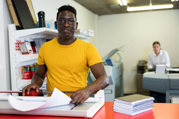 Portrait of positive male employee of a printing house with projects in hands