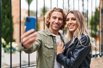 Obraz premium Man and woman couple smiling confident make selfie by the smartphone at street