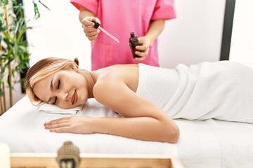Obraz na płótnie Canvas Young caucasian woman lying on table having back massage using oil at beauty salon